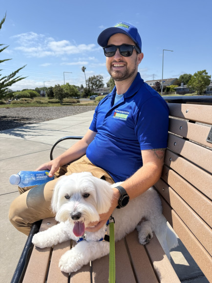 Dog trainer resting on a bench with a small white dog