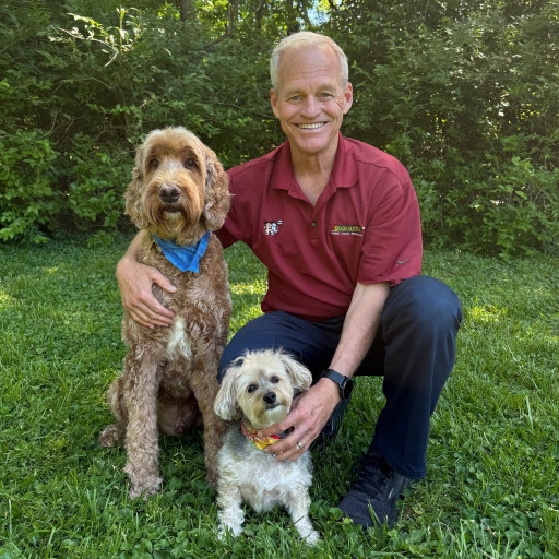 Dog trainer in louisville kentucky in a grassy field with two well behaved dogs