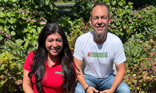 Two dog trainers in a sunny park with three dogs